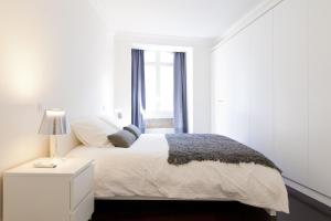ein weißes Schlafzimmer mit einem weißen Bett und einem Fenster in der Unterkunft FLH Baixa Elegant Apartment in Lissabon