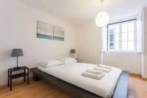um quarto com uma cama com lençóis brancos e uma janela em FLH Baixa Trendy Apartment em Lisboa