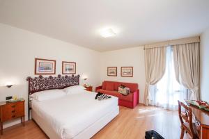 a bedroom with a white bed and a red couch at Hotel Garden in Siena