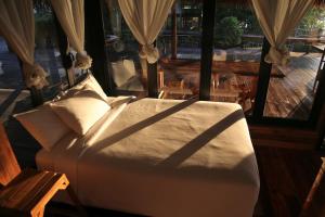 a bed in a room with a view of a patio at Baan​ Tonlamphu​ Pakpra in Phatthalung