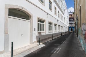 ein weißes Gebäude mit einer weißen Garagentür auf einer Straße in der Unterkunft FLH Cais Sodré Charming Flat in Lissabon