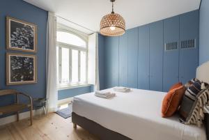 ein blaues Schlafzimmer mit einem großen Bett und einem Kronleuchter in der Unterkunft FLH Cais Sodré Charming Flat in Lissabon