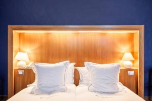 - un lit avec deux oreillers blancs et une tête de lit en bois dans l'établissement Hotel Hof van Aragon, à Lierre
