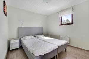 a bedroom with a large bed with white sheets and a window at Fide Äventyrsby & Camping in Fidenäs