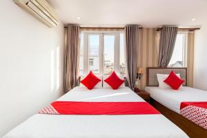 2 łóżka w pokoju hotelowym z czerwonymi poduszkami w obiekcie Hung Phat Hotel - Trung Son w Ho Chi Minh