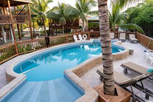 a swimming pool with a palm tree in a resort at Bonita's in Caye Caulker