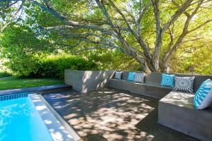 a pool with pillows on a bench next to a tree at Kronendal Heritage in Hout Bay