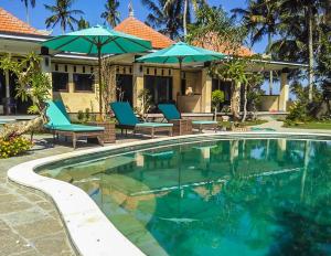 una piscina con sillas y sombrillas junto a una casa en Dana Bali Ricefield Villa, en Candidasa