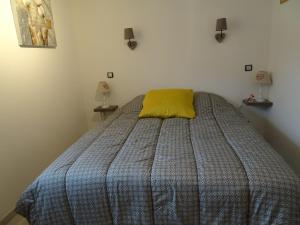 a bedroom with a bed with a yellow pillow on it at Maison d'Hôtes Le Cep d'Or Alsace in Saint-Hippolyte