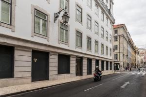リスボンにあるFLH Downtown Fantastic Flatの建物の横の通りをバイクで下る者