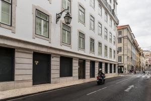 a person riding a motorcycle down a street next to a building at FLH Downtown Fantastic Flat in Lisbon