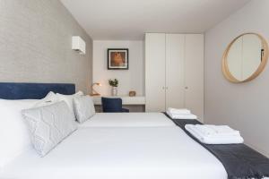 a bedroom with a white bed and a mirror at FLH Chiado Elegant Apartment in Lisbon