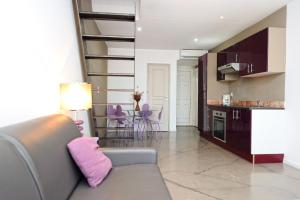 a living room with a couch and a kitchen with purple chairs at Appartement du Tourisme in Zonza