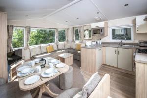 a kitchen and living room of an rv with a table at Combe Martin Beach Holiday Park in Combe Martin