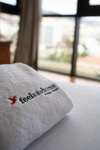 a white pillow with a red logo sitting on a bed at FLH Funchal Amazing Sea View Apartment with Pool in Funchal
