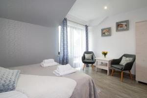 a bedroom with two beds and two chairs and a desk at Za Gościńcem in Kazimierz Dolny