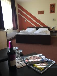 eine Flasche Wein auf einem Tisch neben einem Bett in der Unterkunft City Hotel Agoston in Pécs