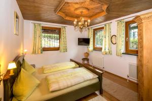 a bedroom with a bed and a chandelier and windows at Ferienhaus Höllbacher in Bad Gastein
