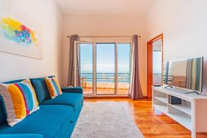 ein Wohnzimmer mit einem blauen Sofa und einem TV in der Unterkunft FLH Funchal Ocean View with Pool in Funchal