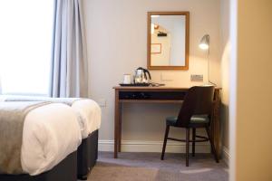 una camera d'albergo con scrivania, letto e specchio di The St George and Dragon by Innkeeper's Collection a Topsham