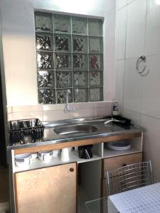 a kitchen with a sink and a shelf with wine glasses at Apartamento de 2 quartos com Ar Condicionado na Enseada in Guarujá