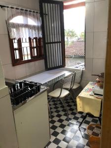 a kitchen with a counter and a sink and a table at Apartamento de 2 quartos com Ar Condicionado na Enseada in Guarujá