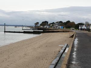 a beach with a pier and the water at island reach in Poole