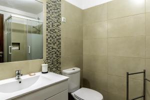 een badkamer met een toilet, een wastafel en een spiegel bij FLH Gaivotas Cozy House in Porches +6 foto's