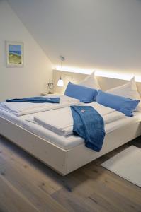 a large white bed with blue pillows on it at Quartier-Restaurant Zum Hannes in Niederhausen