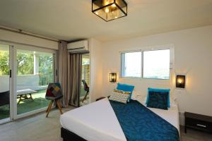 a bedroom with a large bed with blue pillows at Hotel Le Tourisme in Zonza