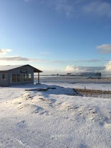 un edificio en la nieve con huellas en la arena en Guesthouse Reynir, en Reynir