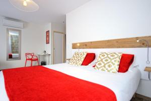 a bedroom with a large white bed with red pillows at Hotel Le Tourisme in Zonza