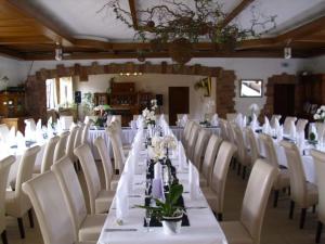 a long dining room with white tables and white chairs at Quartier-Restaurant Zum Hannes in Niederhausen