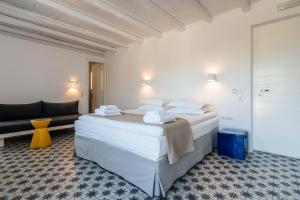 a bedroom with a large white bed and a couch at Milia Gi Suites in Pollonia