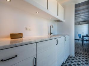 a kitchen with white cabinets and a sink at Milia Gi Suites in Pollonia