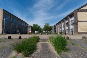 een lege campus met hoog gras voor gebouwen bij Séjour chez le Marin in Le Havre