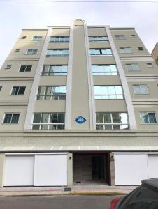 wysoki budynek z samochodem zaparkowanym przed nim w obiekcie Apartamento 2 dormitórios a 350 metros do mar na Meia Praia - Itapema-sc w mieście Itapema