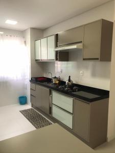 a kitchen with gray cabinets and a black counter top at Apartamento 2 dormitórios a 350 metros do mar na Meia Praia - Itapema-sc in Itapema