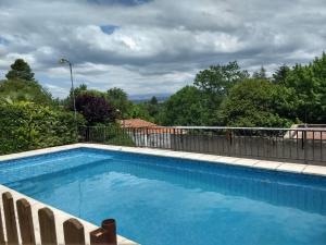 uma grande piscina azul com cerca e árvores em Casa Familiar Villa Carlos Paz em Villa Carlos Paz