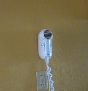 a white phone hanging on a wall next to an outlet at Budgetel Inn & Suites in Rockingham