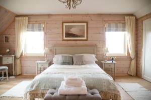 a bedroom with a large bed and two windows at Netherton Farm Lodge in Kemnay