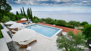 a swimming pool with umbrellas and a view of the water at Smještaj -SOBE PIA in Mošćenička Draga