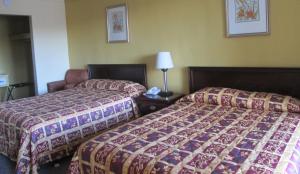 a hotel room with two beds and a lamp at Budgetel Inn & Suites in Rockingham