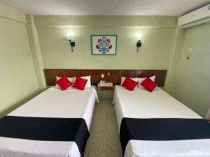 two beds in a hotel room with red pillows at Hotel Batab in Cancún