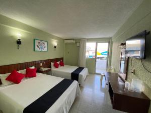 a hotel room with two beds and a television at Hotel Batab in Cancún