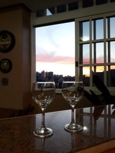 zwei Weingläser auf einem Tisch vor einem Fenster in der Unterkunft Hotel Mont Blanc in Bento Gonçalves