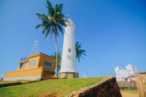 a lighthouse on top of a hill with a palm tree at Antic Guesthouse - Galle Fort in Galle