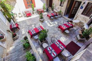 - une vue sur la terrasse dotée de tables et de chaises rouges dans l'établissement Palace Derossi, à Trogir