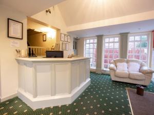 a hotel lobby with a reception desk and a chair at Wincham Hall Hotel in Northwich