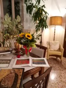 a dining room table with a vase of sunflowers on it at Bed&Breakfast 1912 in Fermo